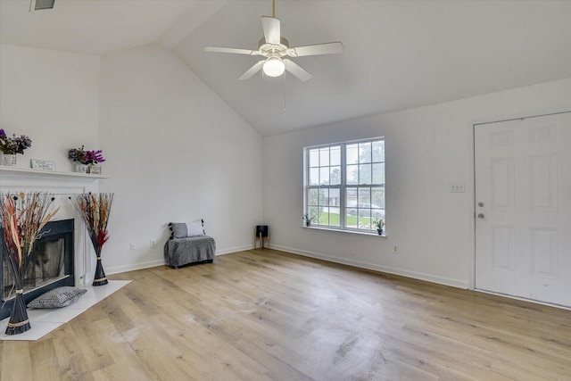 unfurnished living room featuring a tile fireplace, light wood-type flooring, vaulted ceiling, and ceiling fan