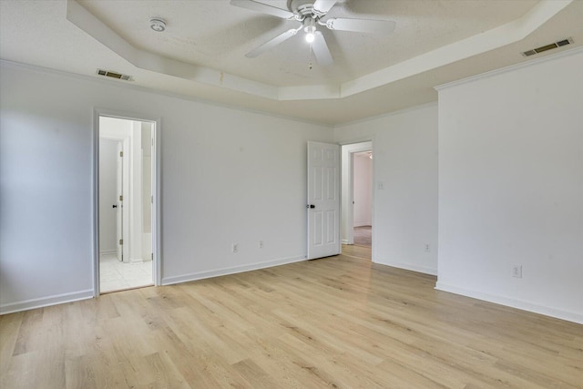 spare room featuring a textured ceiling, a tray ceiling, light hardwood / wood-style flooring, and ceiling fan