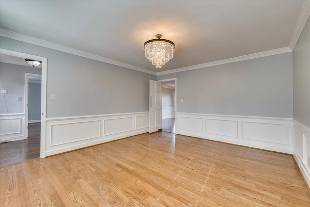 empty room with crown molding, a chandelier, and light wood-type flooring