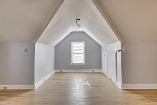 additional living space with light hardwood / wood-style flooring and vaulted ceiling