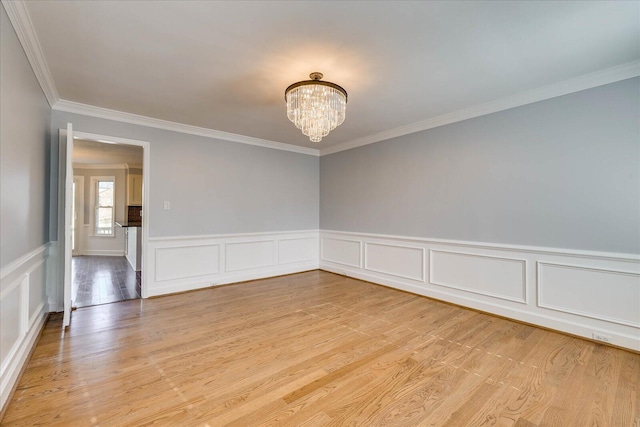 unfurnished room with ornamental molding, a notable chandelier, and light hardwood / wood-style floors