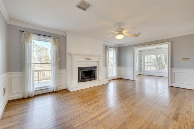 unfurnished living room with ornamental molding, light hardwood / wood-style floors, and a brick fireplace