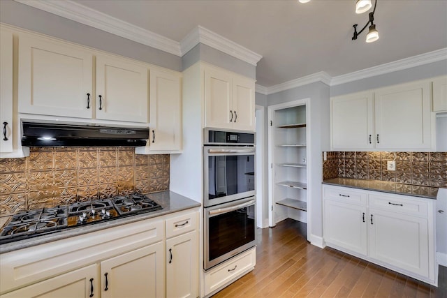 kitchen with stainless steel appliances, crown molding, backsplash, and light wood-type flooring