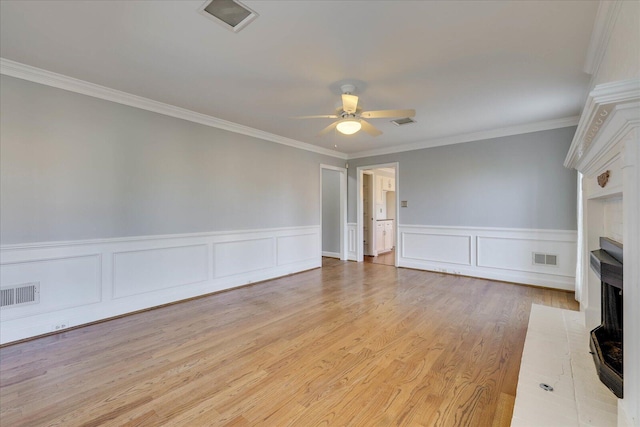 unfurnished living room featuring crown molding, a large fireplace, ceiling fan, and light hardwood / wood-style flooring