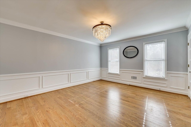 empty room featuring a notable chandelier, light hardwood / wood-style flooring, and a wealth of natural light