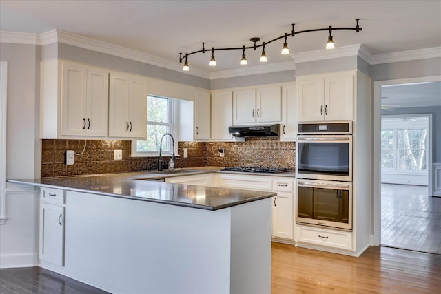 kitchen featuring appliances with stainless steel finishes, sink, white cabinets, kitchen peninsula, and light hardwood / wood-style flooring