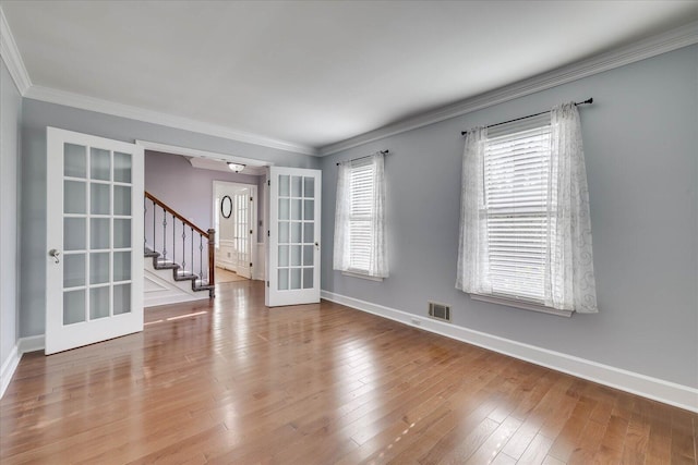 unfurnished room featuring ornamental molding, a wealth of natural light, light wood-type flooring, and french doors