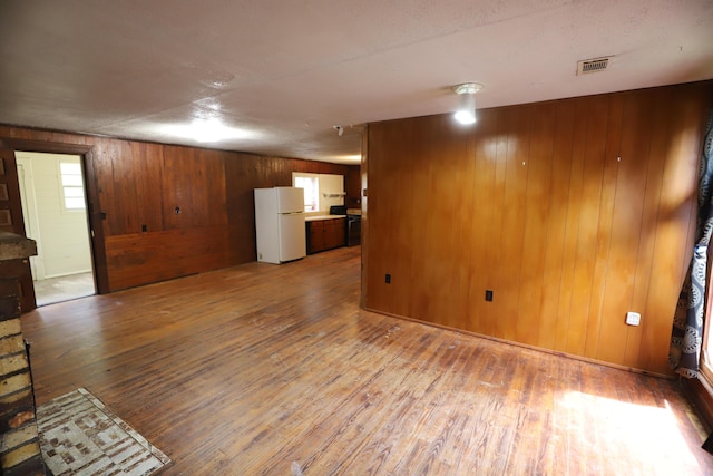 unfurnished living room with hardwood / wood-style floors and wood walls