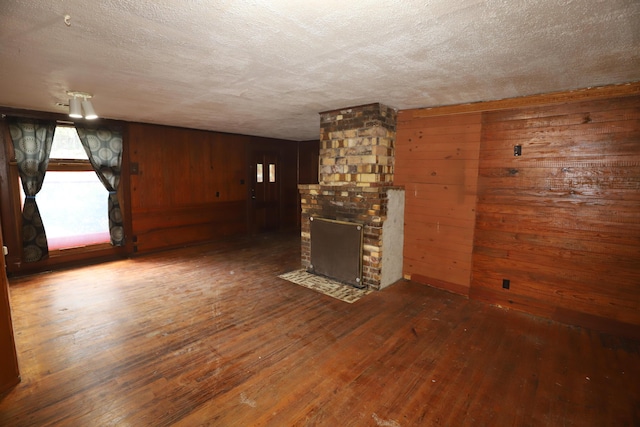 unfurnished living room featuring hardwood / wood-style floors, a textured ceiling, a fireplace, and wood walls