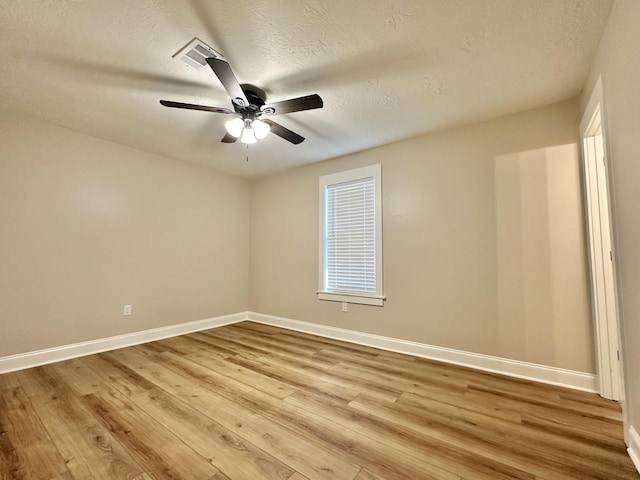 empty room with baseboards, visible vents, light wood finished floors, ceiling fan, and a textured ceiling