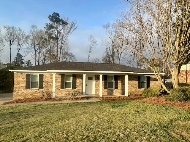 ranch-style home featuring brick siding, covered porch, and a front yard