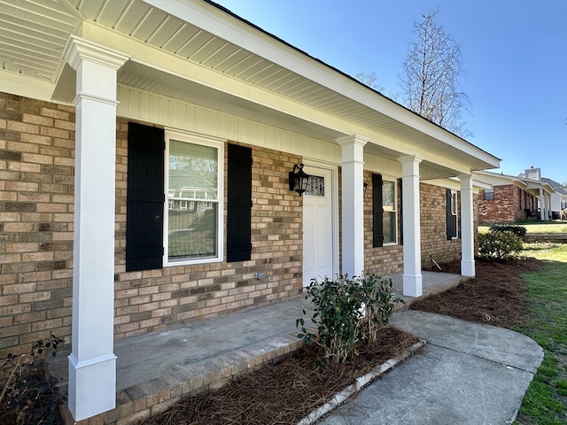 property entrance featuring brick siding and a porch