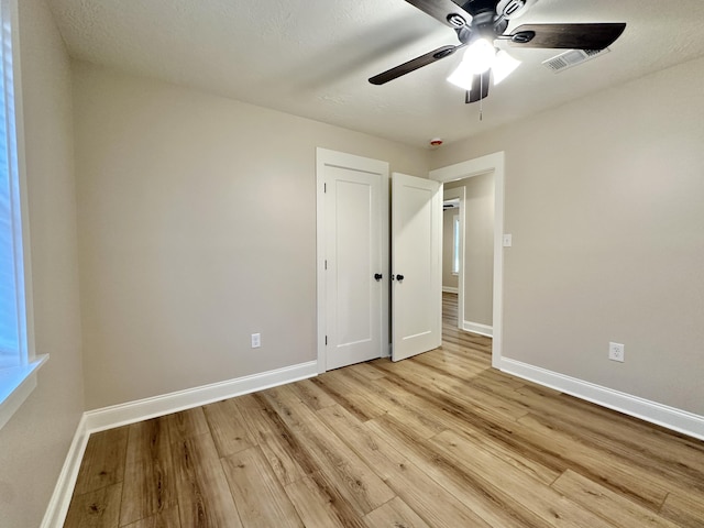 unfurnished bedroom with visible vents, light wood-style floors, baseboards, and ceiling fan