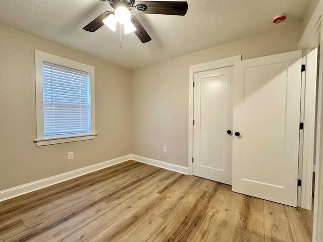 unfurnished bedroom featuring a closet, baseboards, ceiling fan, and light wood finished floors