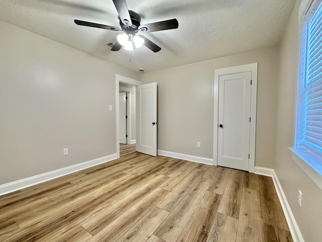 unfurnished bedroom with baseboards, light wood-style floors, ceiling fan, and a textured ceiling