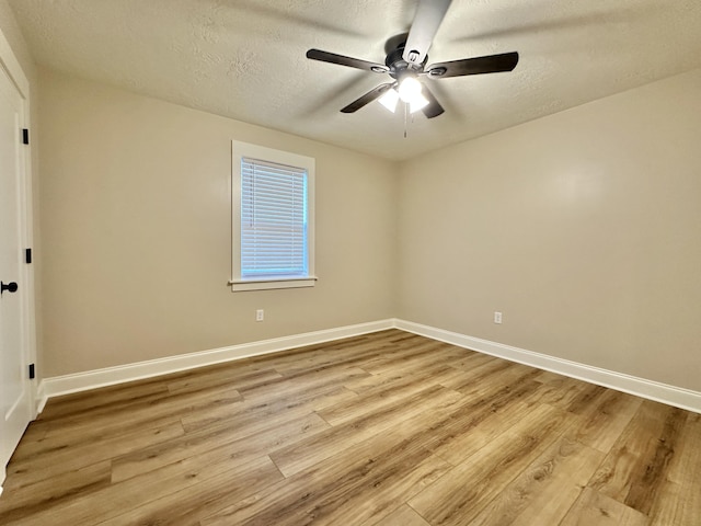 unfurnished room featuring a textured ceiling, baseboards, and wood finished floors