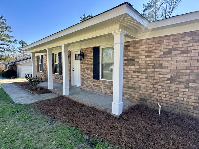 view of exterior entry with covered porch and brick siding