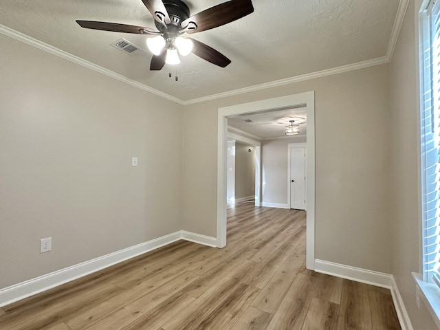 empty room featuring crown molding, a ceiling fan, visible vents, and light wood finished floors