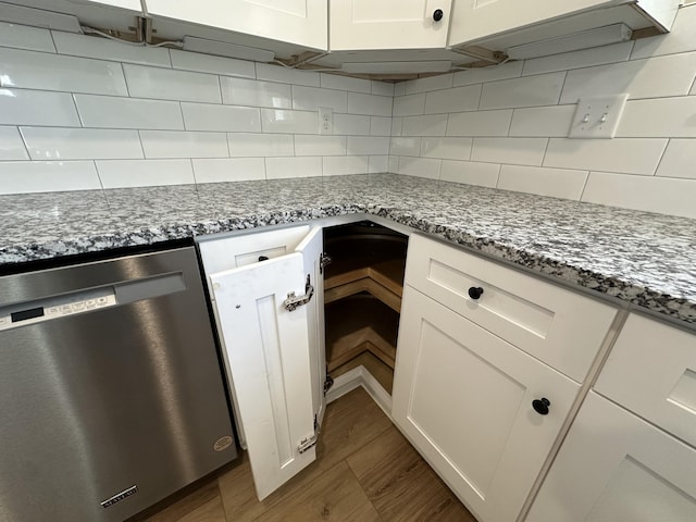 kitchen featuring wood finished floors, white cabinetry, stone countertops, dishwasher, and backsplash