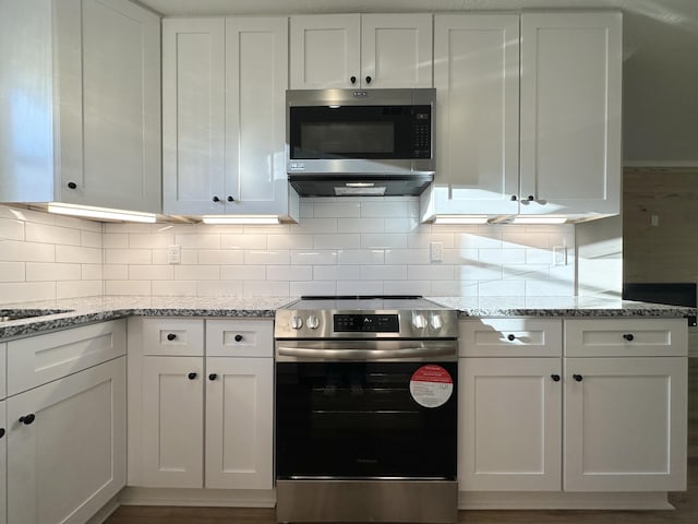 kitchen with light stone counters, tasteful backsplash, appliances with stainless steel finishes, and white cabinets