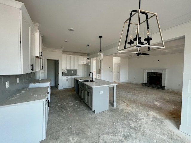 kitchen with a fireplace, white cabinets, a sink, and open floor plan