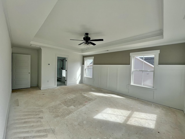 unfurnished bedroom with a wainscoted wall, a tray ceiling, a decorative wall, and ornamental molding