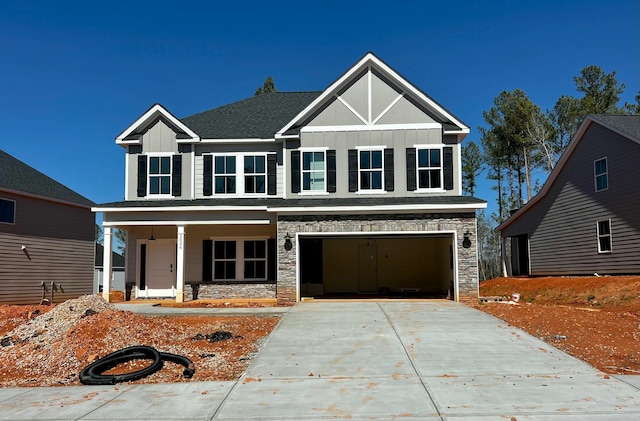 view of front of home with covered porch, an attached garage, board and batten siding, stone siding, and driveway