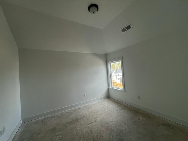 empty room with lofted ceiling, visible vents, and baseboards