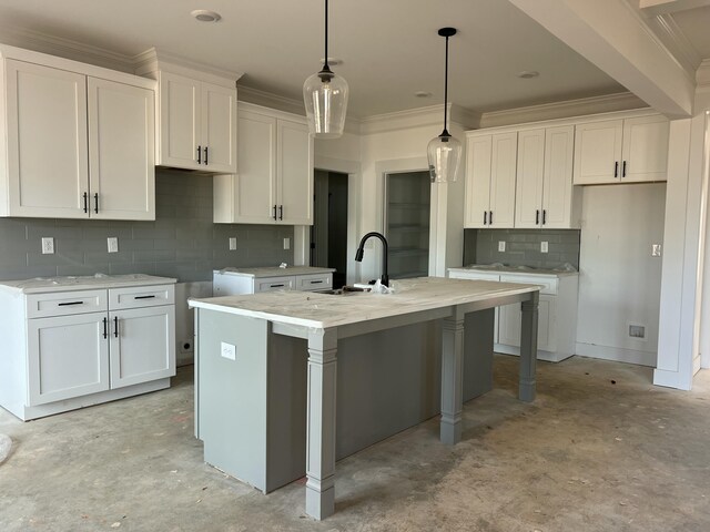 kitchen featuring concrete flooring, a sink, a center island with sink, and white cabinetry