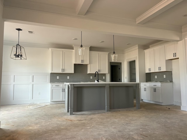 kitchen with white cabinetry, a kitchen island with sink, visible vents, and pendant lighting