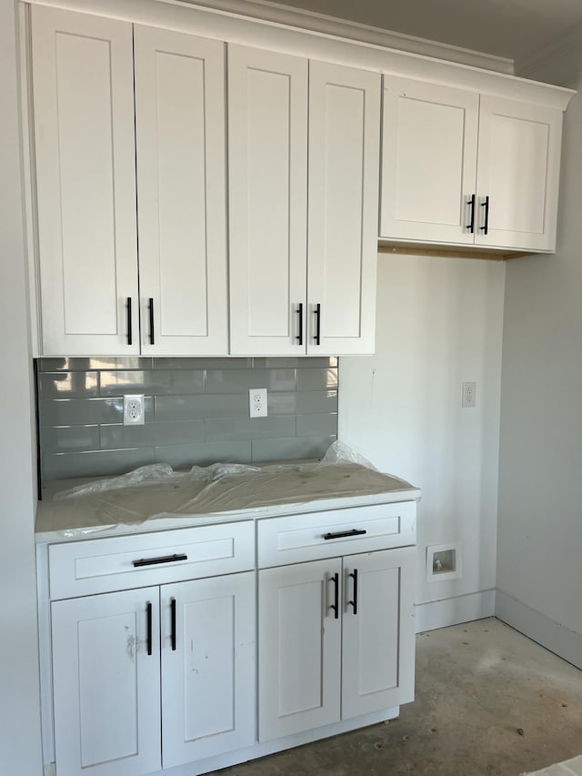 bar featuring concrete flooring, backsplash, and baseboards