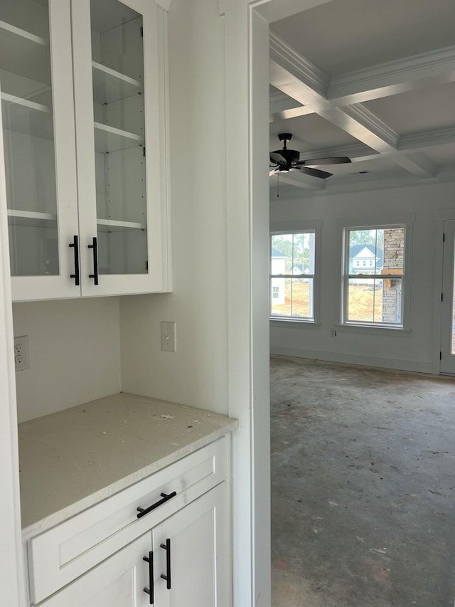 interior space featuring ceiling fan, unfinished concrete flooring, coffered ceiling, and beam ceiling