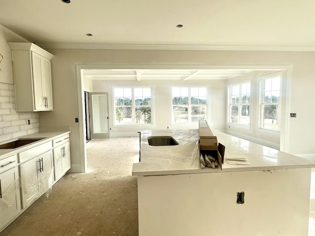 kitchen with plenty of natural light, white cabinets, crown molding, and a center island