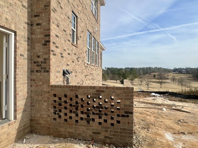 view of property exterior with a rural view and brick siding