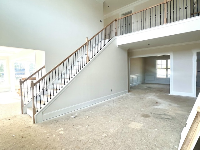 stairway with ornamental molding, baseboards, and a high ceiling