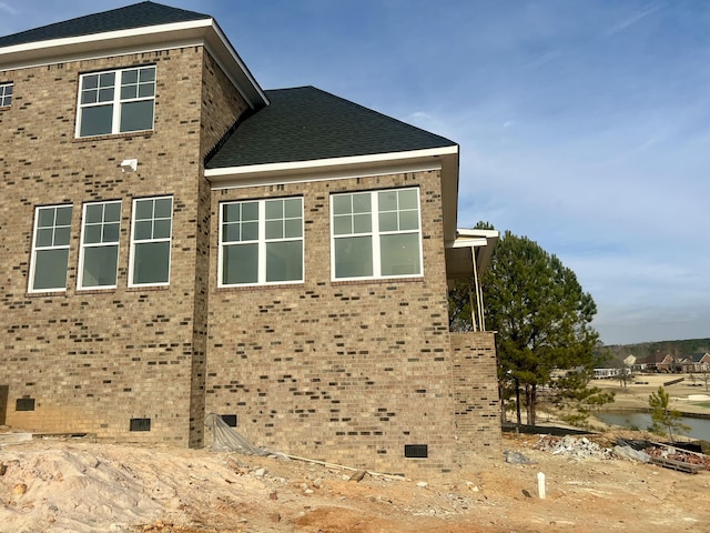 view of property exterior with crawl space, roof with shingles, and brick siding