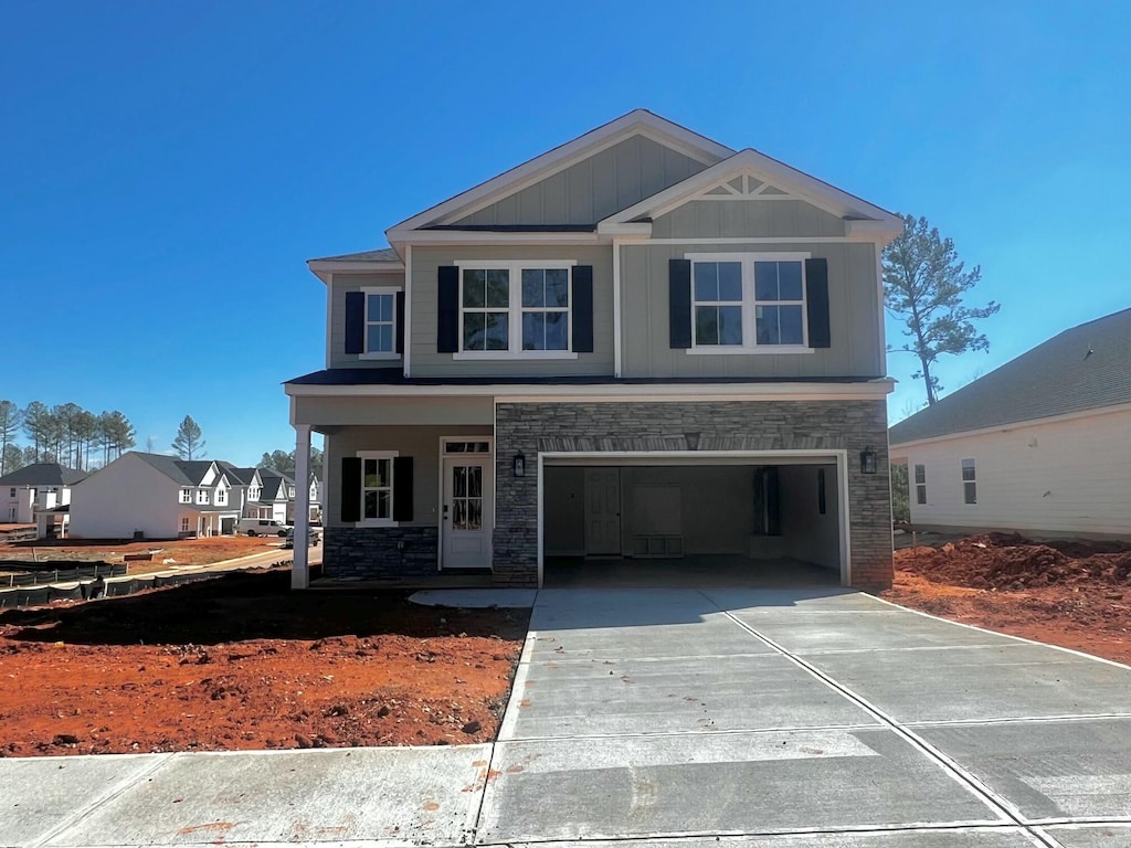 view of front of house with a garage, stone siding, driveway, and board and batten siding