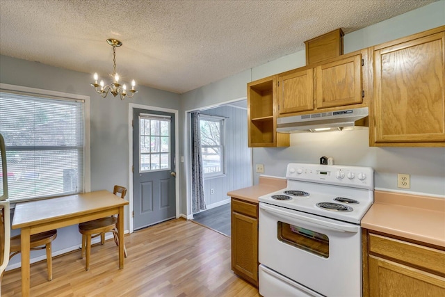 kitchen featuring light wood-style flooring, hanging light fixtures, light countertops, white electric range, and under cabinet range hood