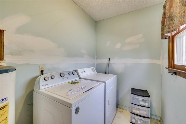 clothes washing area featuring water heater, laundry area, a textured ceiling, and independent washer and dryer