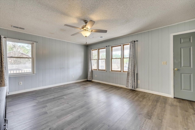 spare room featuring plenty of natural light, baseboards, ceiling fan, and wood finished floors