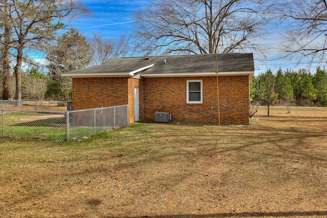 back of property featuring cooling unit, brick siding, a lawn, and fence