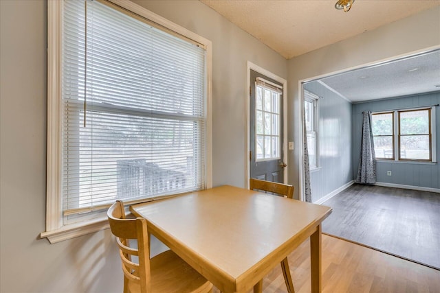 dining space with a textured ceiling, baseboards, and wood finished floors