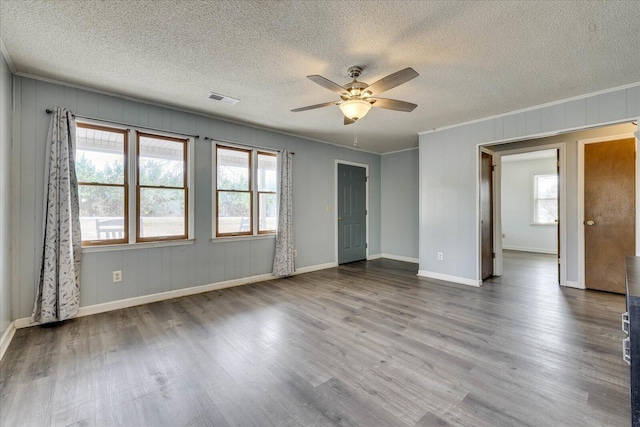 spare room featuring baseboards, visible vents, wood finished floors, and ornamental molding