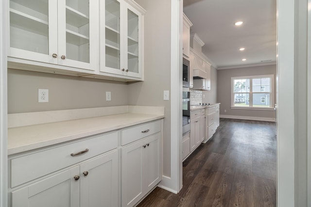 kitchen featuring white cabinetry, stainless steel appliances, dark hardwood / wood-style flooring, backsplash, and ornamental molding