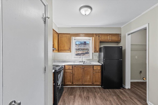 kitchen featuring dark wood-type flooring, ornamental molding, black appliances, and sink