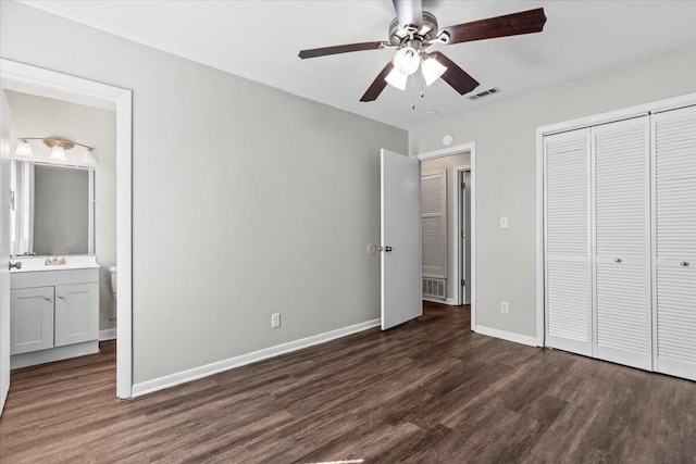 unfurnished bedroom featuring ceiling fan, a closet, ensuite bath, and dark hardwood / wood-style floors