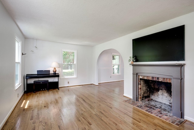 3103 Holly Haven Dr, Augusta, GA 30907 - living room featuring arched walkways, a brick fireplace, wood finished floors, and a textured ceiling