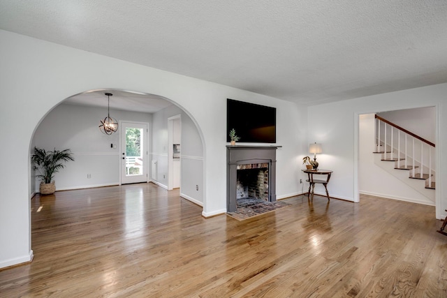 3103 Holly Haven Dr, Augusta, GA 30907 - unfurnished living room with wood finished floors, arched walkways, a brick fireplace, and a textured ceiling
