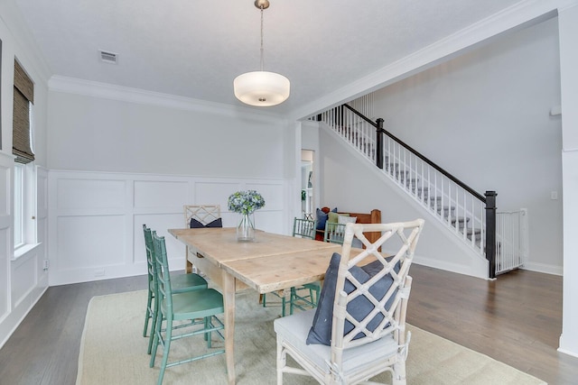 dining room with ornamental molding, dark wood-style floors, stairway, a decorative wall, and wainscoting