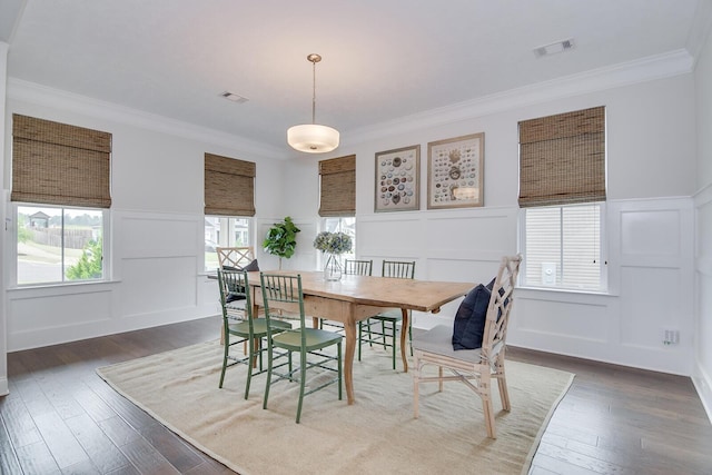 dining room with a decorative wall, crown molding, wood-type flooring, and wainscoting